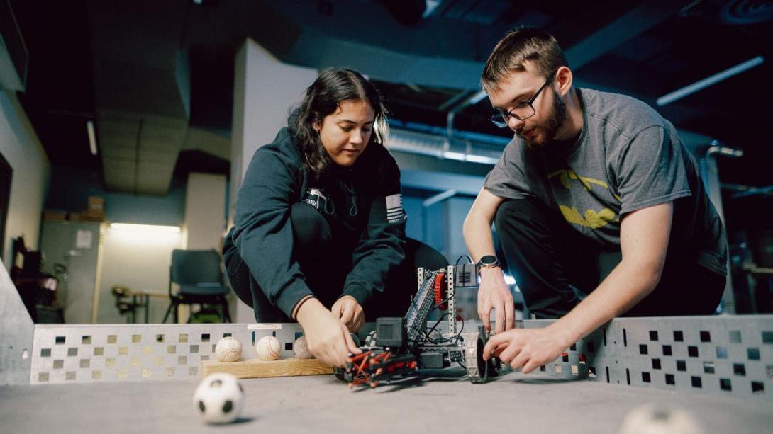 Two Kettering engineering students prepare to test a robot in a course filled with miniature balls